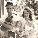 A couple holding a baby and a dog