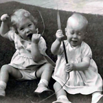 Two infants holding blades of grass